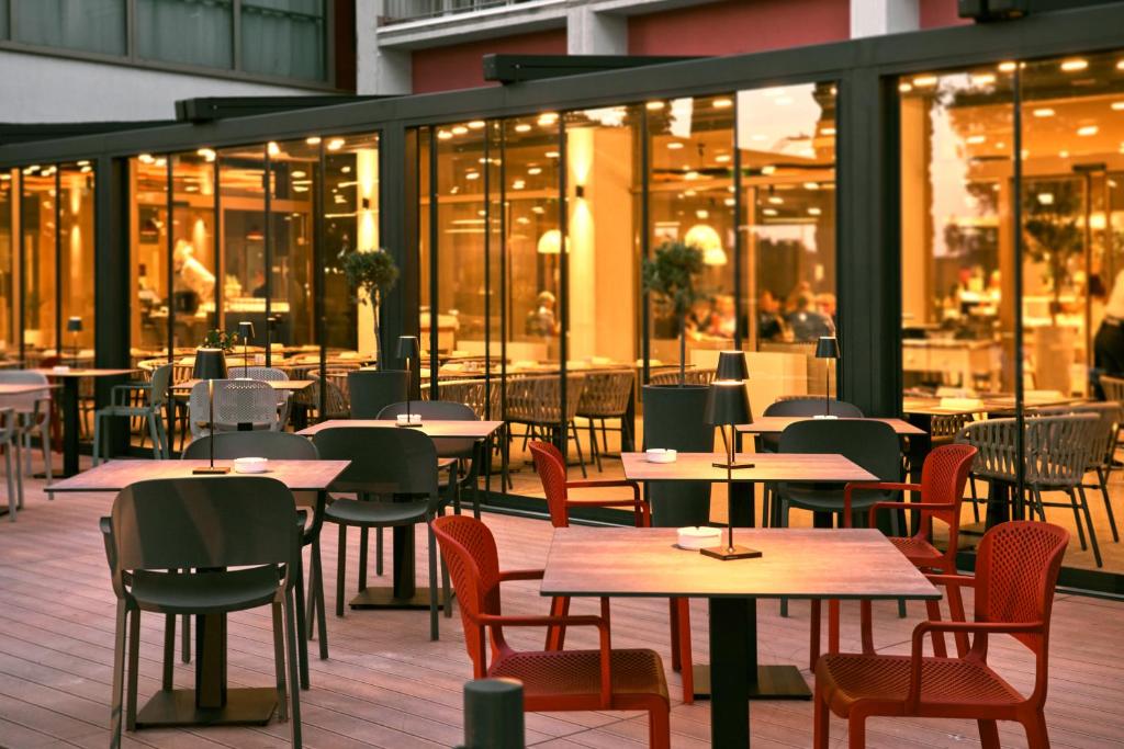 ein leeres Restaurant mit Tischen, Stühlen und Fenstern in der Unterkunft Remisens Hotel LUCIJA in Portorož