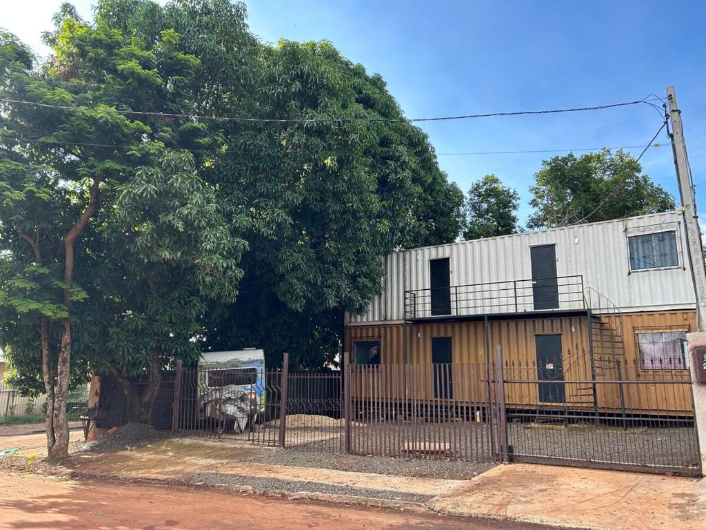 a building with a fence next to a tree at Kitinete perto da Itaipu e Unioeste in Foz do Iguaçu