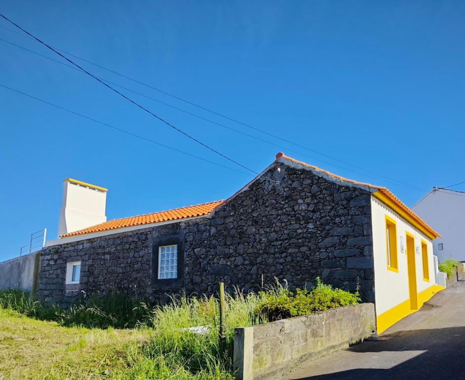 ein altes Steinhaus mit einem gelben und schwarzen Gebäude in der Unterkunft Casa da Marta - Azorean Nature Escape in Nordeste