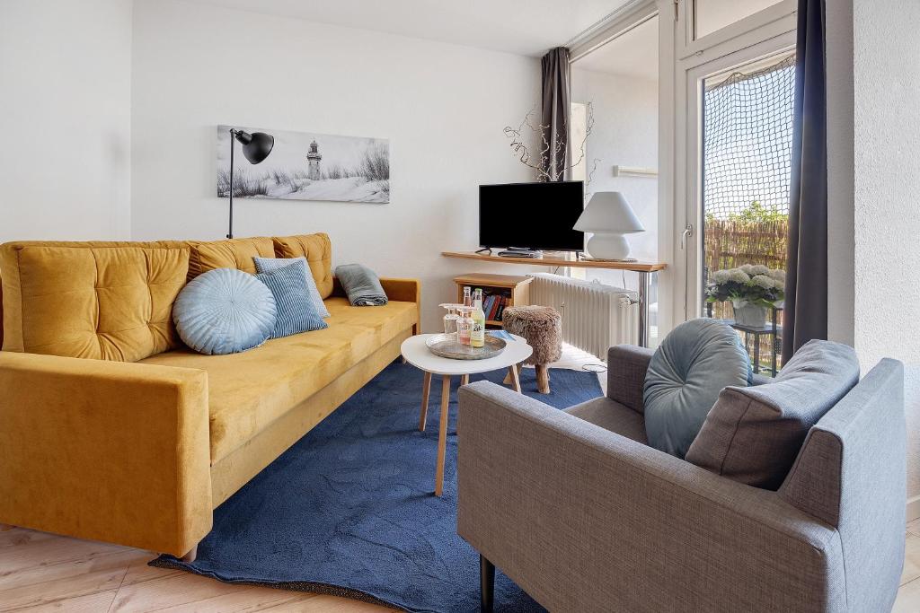 a living room with a yellow couch and two chairs at Fräulein Frida Steinhude in Wunstorf