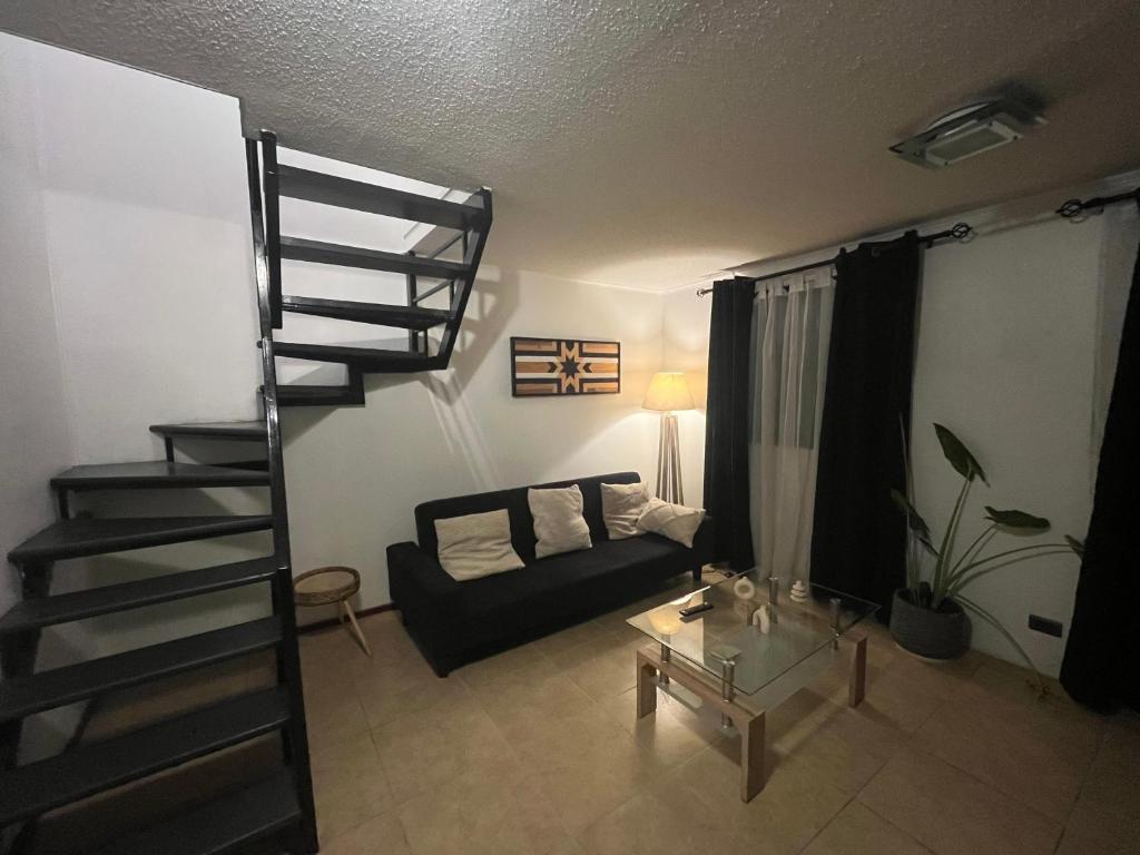a living room with a spiral staircase and a couch at Tu Espacio RE - Casa cerca del Aeropuerto in Santiago
