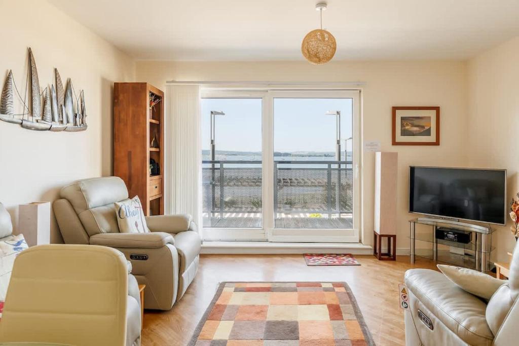 a living room with a large window and a tv at Ahoy - Balcony with Beautiful Harbour Views in Poole