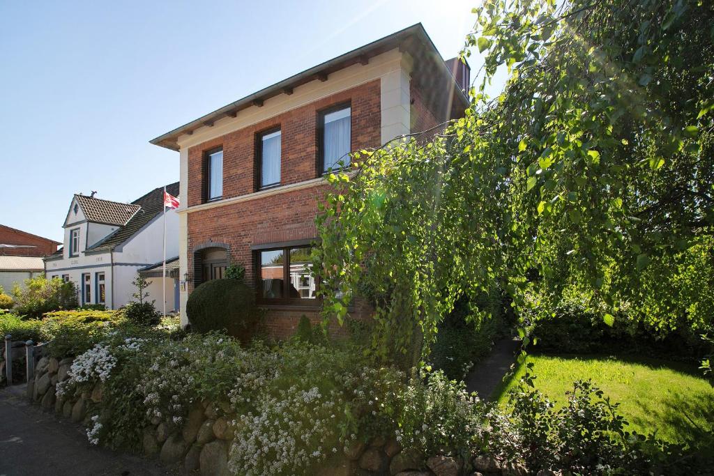 a brick house with a stone fence in front of it at Die Kleine Ferienvilla in Wesselburen