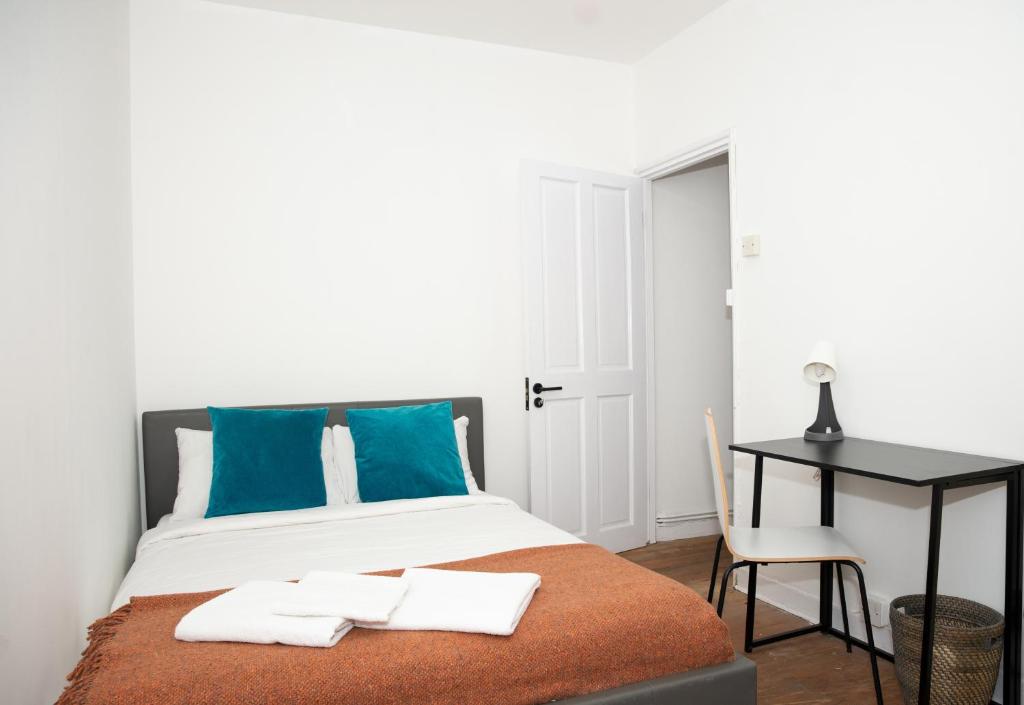 a bedroom with a bed with blue pillows and a desk at Stay by the West End - Central Apartment in London