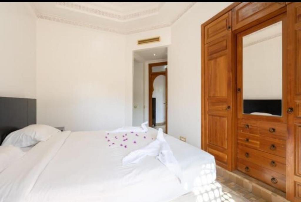 a bedroom with a white bed and a wooden cabinet at Palmeraie Village 2 in Marrakesh