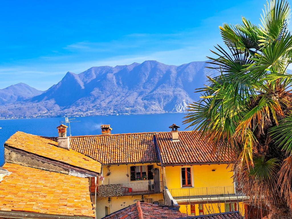 a yellow house with a palm tree and mountains in the background at La Palma in Ghiffa