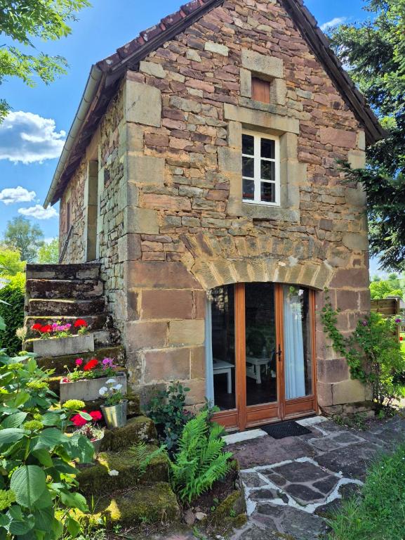 une maison en pierre avec une porte et quelques fleurs dans l'établissement L'herbe est plus verte, à Beynat
