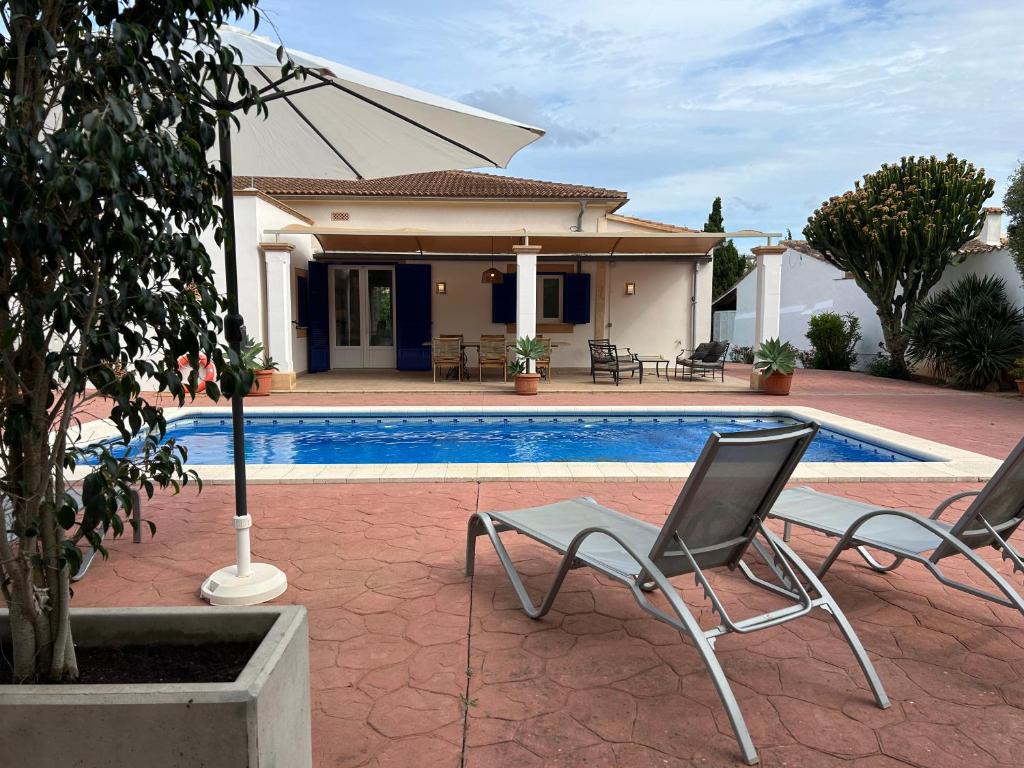 a swimming pool with two chairs and a house at Villa A&M. Beautiful House in Puerto de Andratx in Port d’Andratx