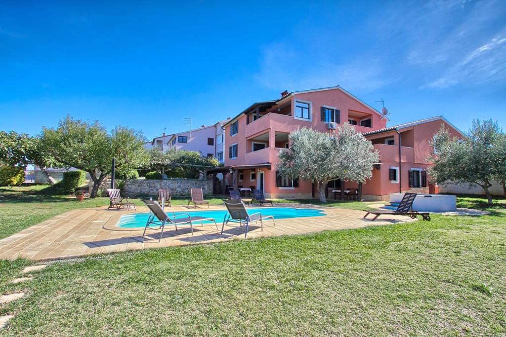 ein Haus mit Stühlen und einem Pool im Garten in der Unterkunft Apartments Aldo in Banjole