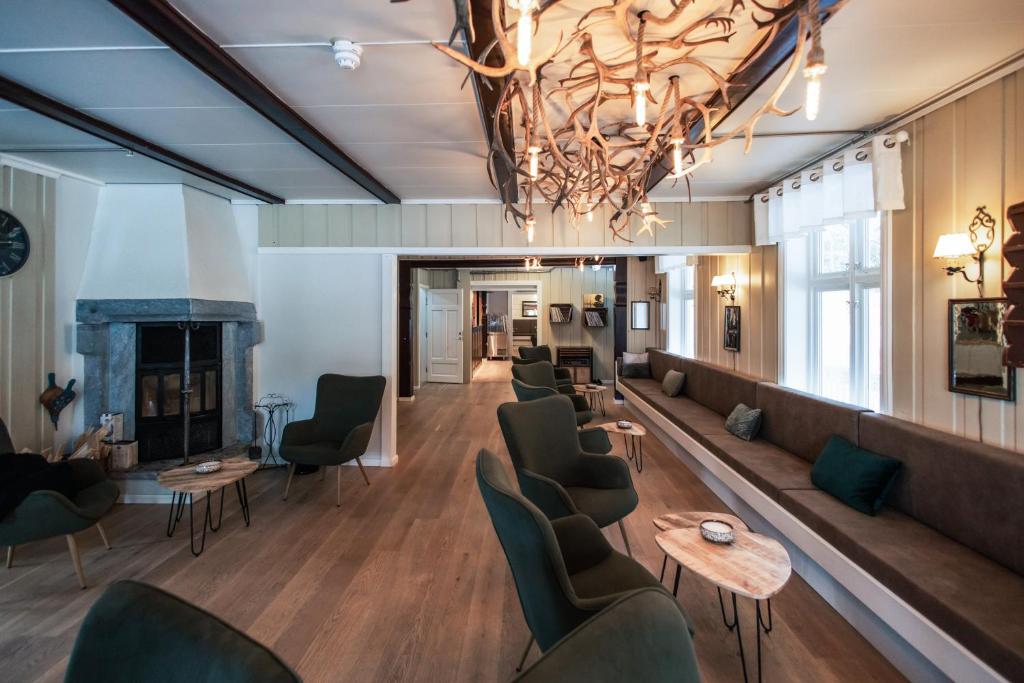 a lobby with chairs and a fireplace and a chandelier at Heartbreak Hotel in Nedre Heidal