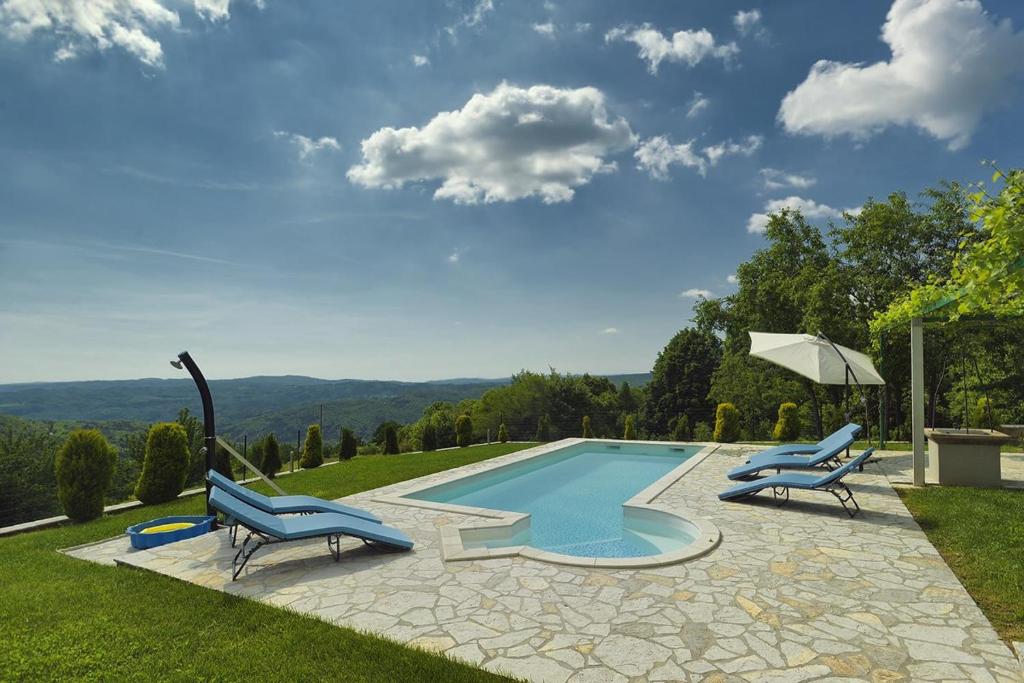 a swimming pool with two blue chairs and an umbrella at Villa Bella in Paz