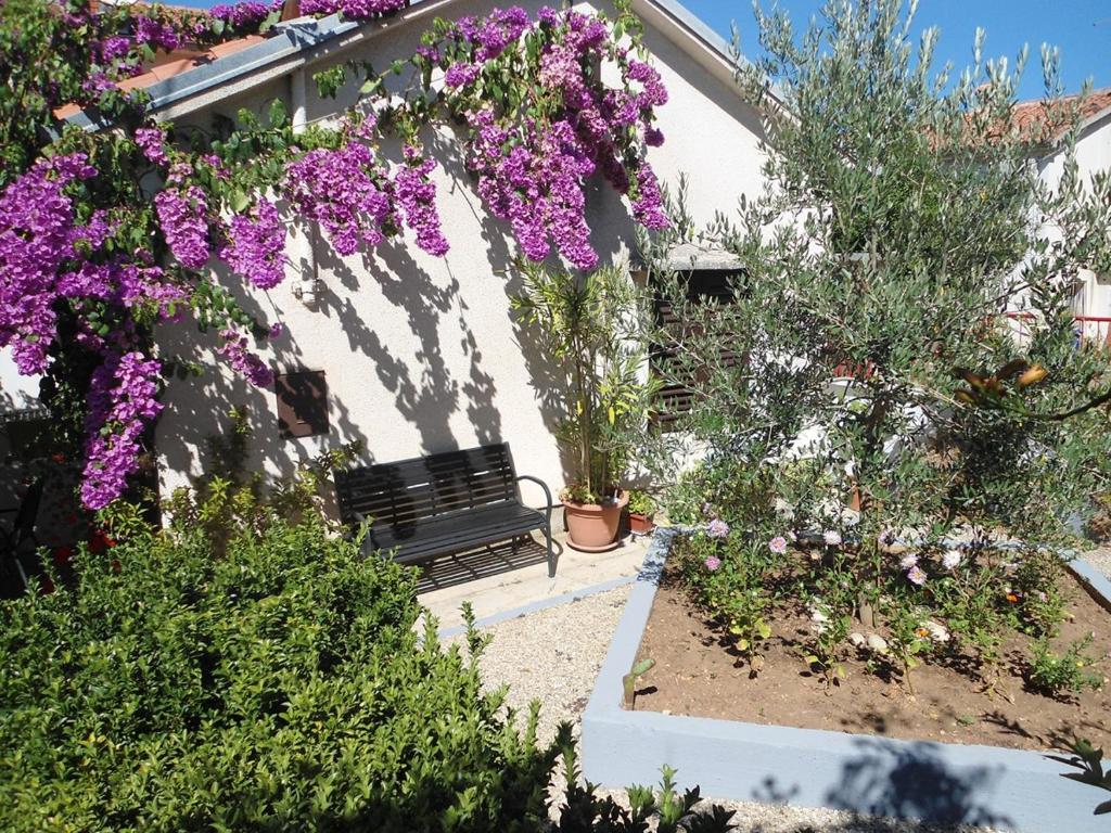 a bench sitting in a garden with purple flowers at Apartments Aurora in Pomer