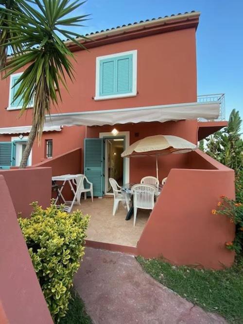 une maison avec un patio avec une table et un parasol dans l'établissement MORIANI PLAGE - 3 pièces climatisé 4 à 6 couchages D1, à Moriani-Plage