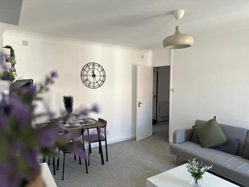 a living room with a table and a clock on the wall at Stylish 2 Bedroom Flat Slough in Slough