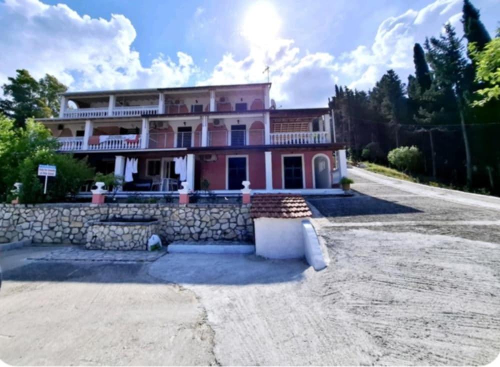 een groot roze huis met een stenen muur bij Villa Danai in Agios Georgios Pagon