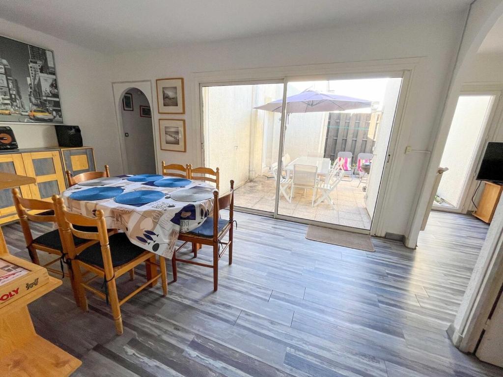 une salle à manger avec une table, des chaises et un parasol dans l'établissement Maison Bord de Mer 6 à 7 pers au Grau du Roi, au Grau-du-Roi