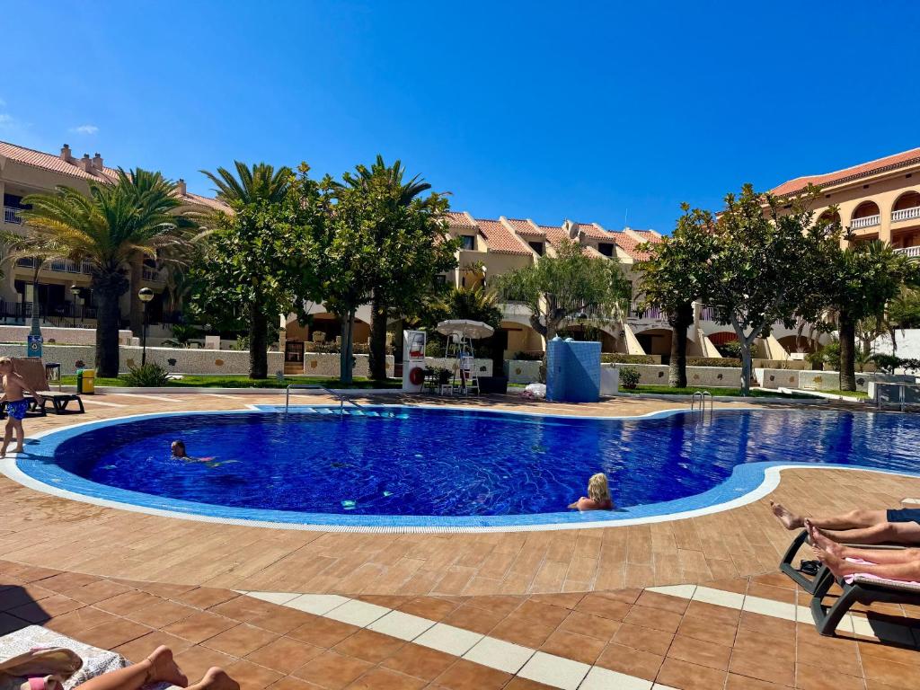 a large swimming pool with people sitting in chairs around it at Golden Mile Getaway - Las Americas Tenerife in Playa de las Americas