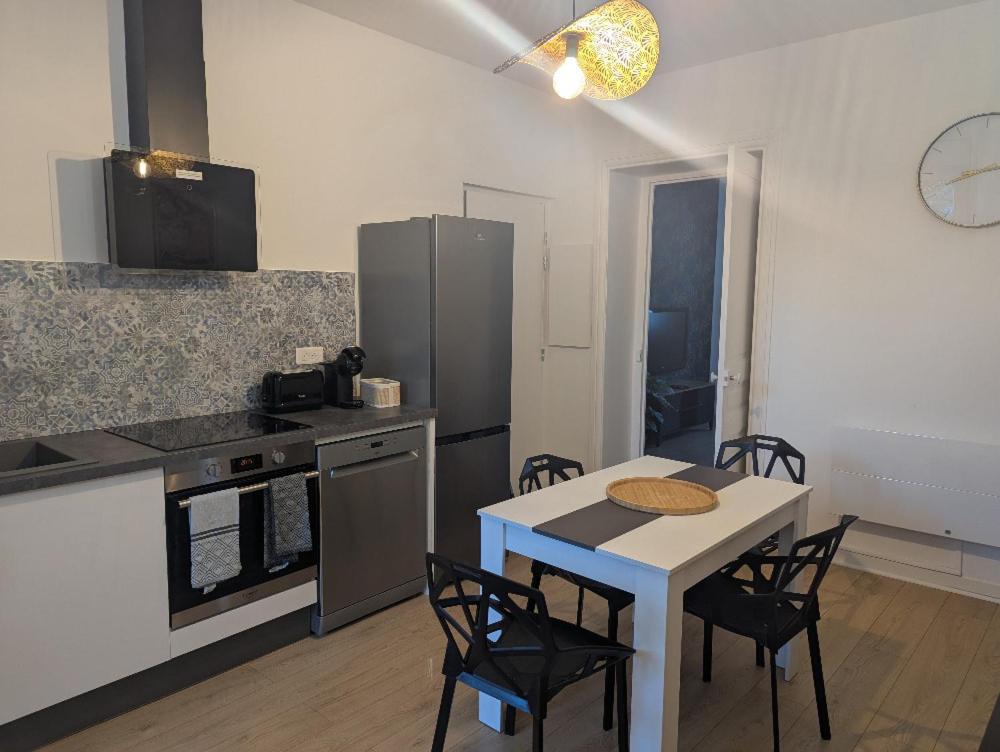 a kitchen with a table and some chairs and a table and a counter at Le petit cocon de Montrond in Montrond-les-Bains