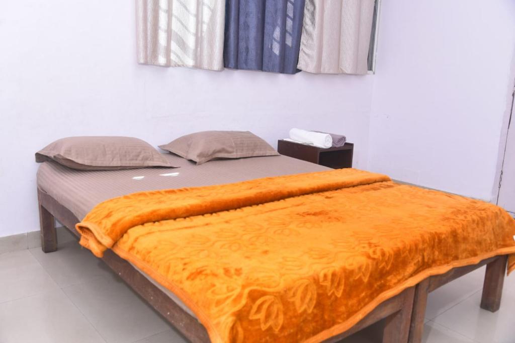 a bed with an orange blanket on top of it at Sai Comforts in Jāmb