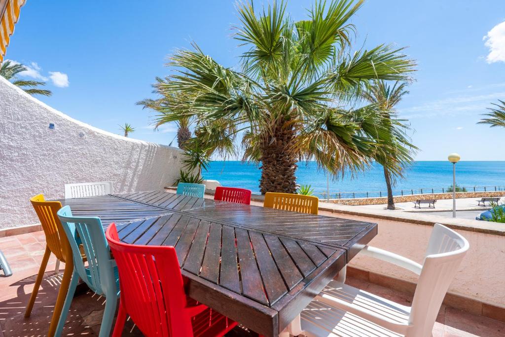 a wooden table and chairs with the beach in the background at Hauzify I Casa Mirador 8 in L'Ametlla de Mar