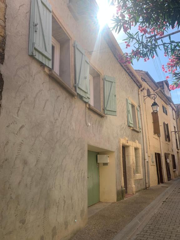 un bâtiment avec une porte verte et des fenêtres donnant sur une rue dans l'établissement Laudacieuse, à Cazouls-lès-Béziers