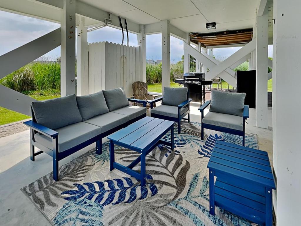 een veranda met een bank, twee stoelen en een piano bij Otter Oasis in Surf City