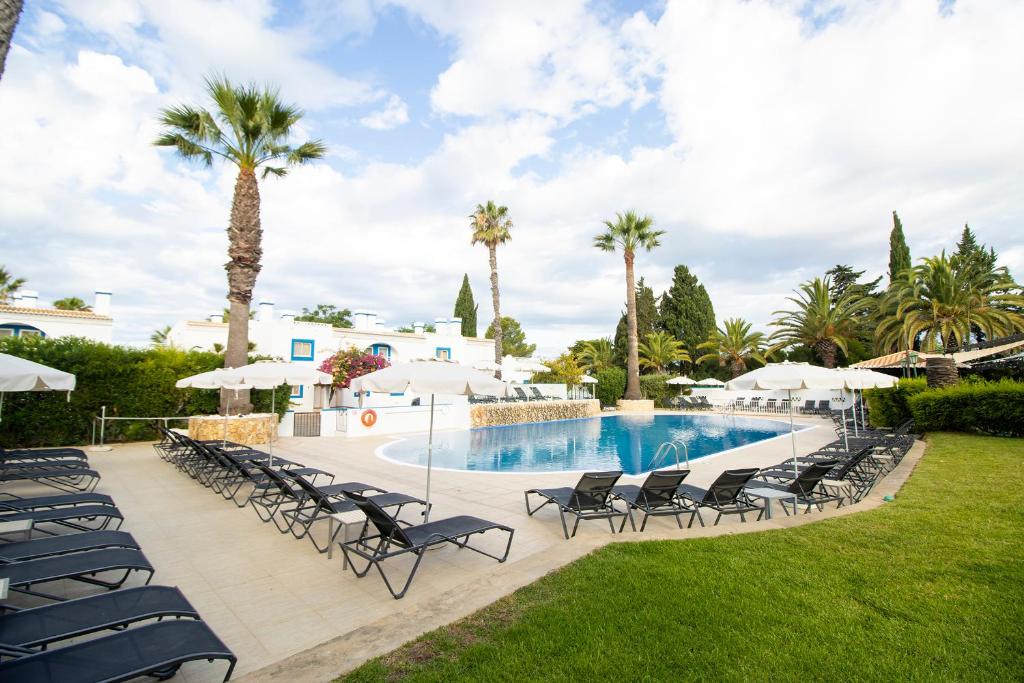 a resort pool with chairs and palm trees at Pestana Palm Gardens in Carvoeiro