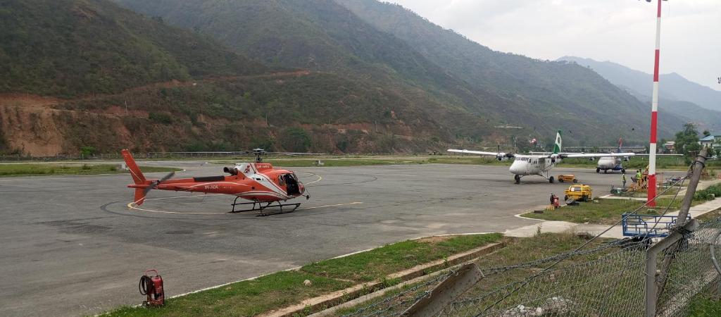 un elicottero rosso è parcheggiato su una pista con montagne di Anil Guest house and khajaghar a Rāmechhāp