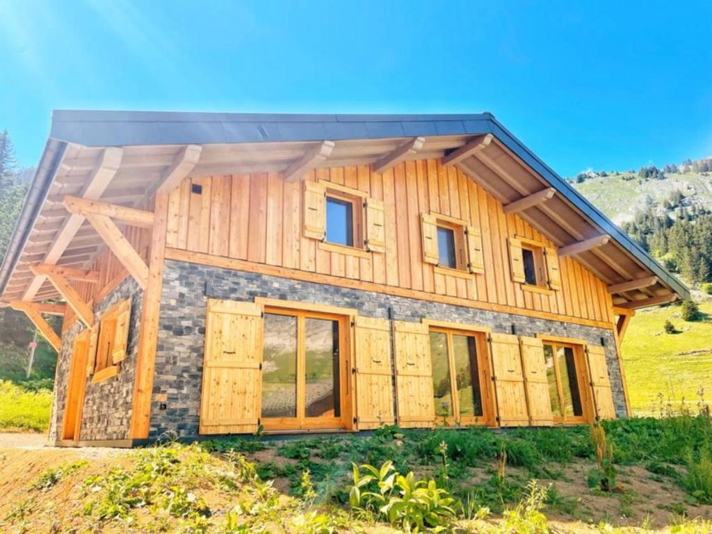 una casa de madera con puertas y ventanas en una colina en Les Carroz de Mary - Sommand, en Mieussy
