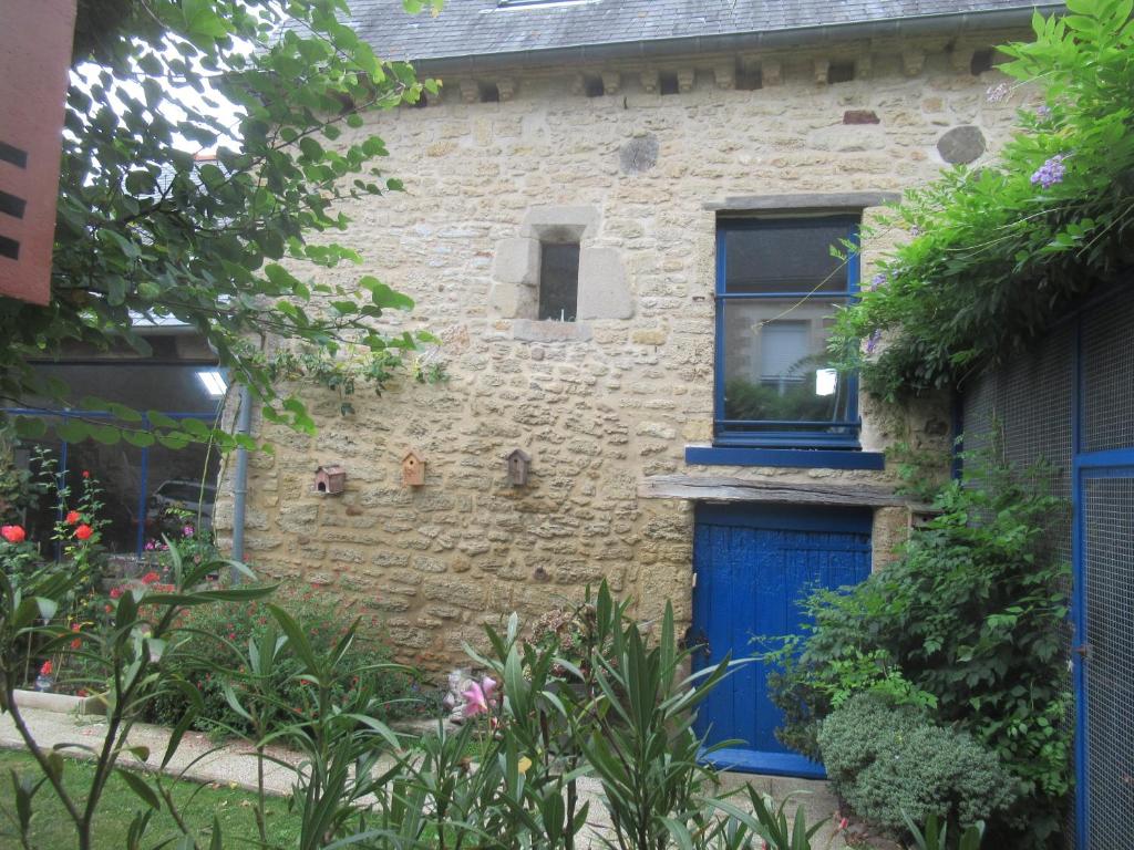 a brick house with a blue door and a window at La forge in Le Quiou
