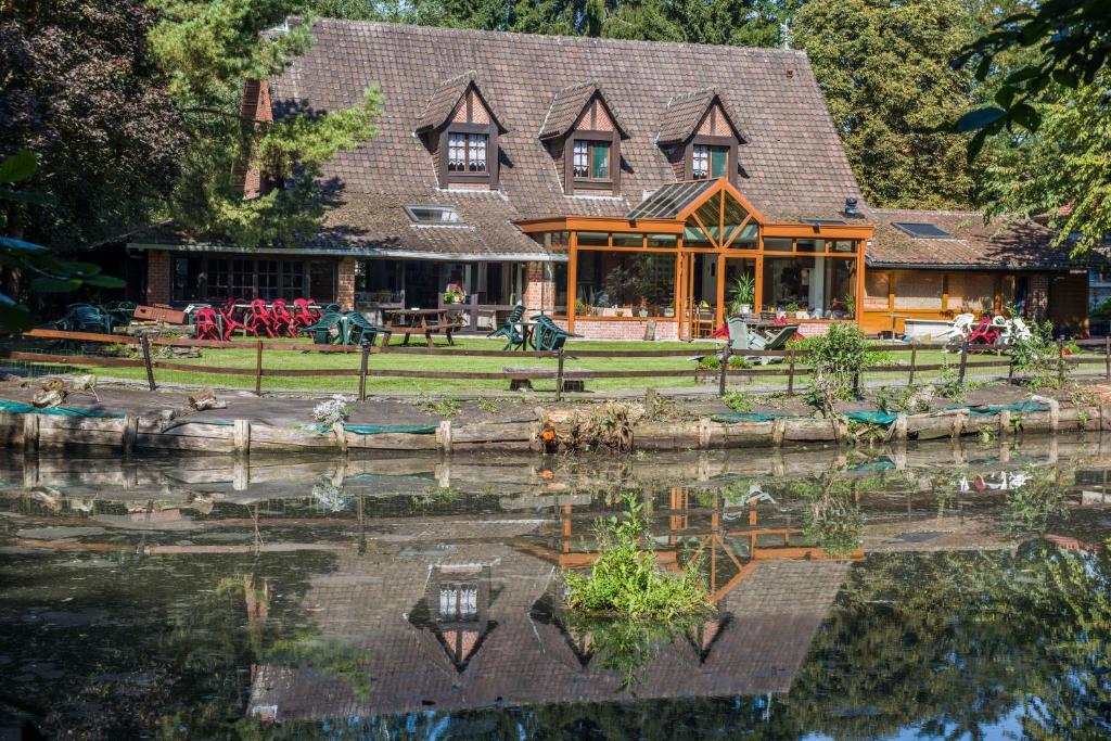 une grande maison avec un étang en face de celle-ci dans l'établissement AUBERGE du BORD des EAUX - Demi-pension assurée sur réservation, à Saint-Amand-les-Eaux