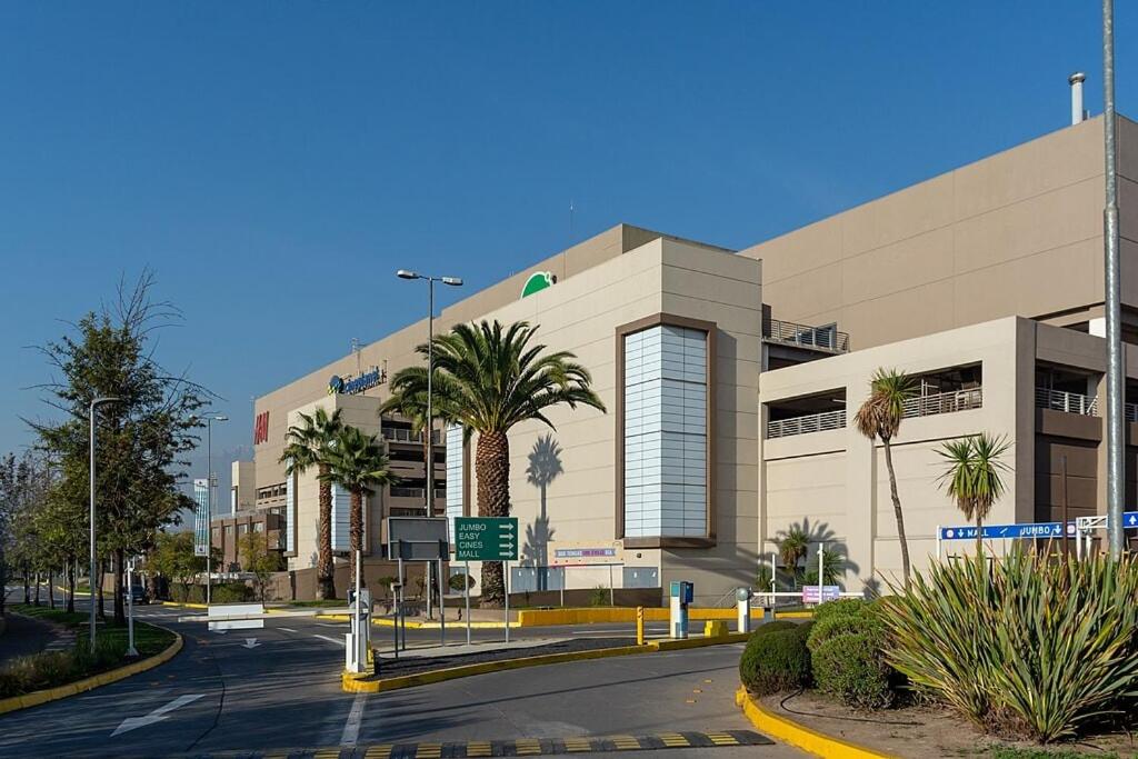a building with palm trees in front of a street at Steps from the subway and Free Parking in Santiago
