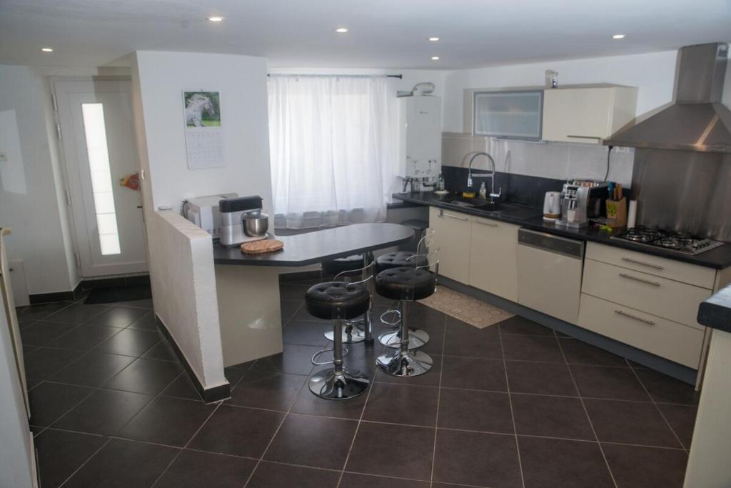 une cuisine avec un comptoir et des tabourets. dans l'établissement Maison de ville meublée 60m2, à Saint Etienne