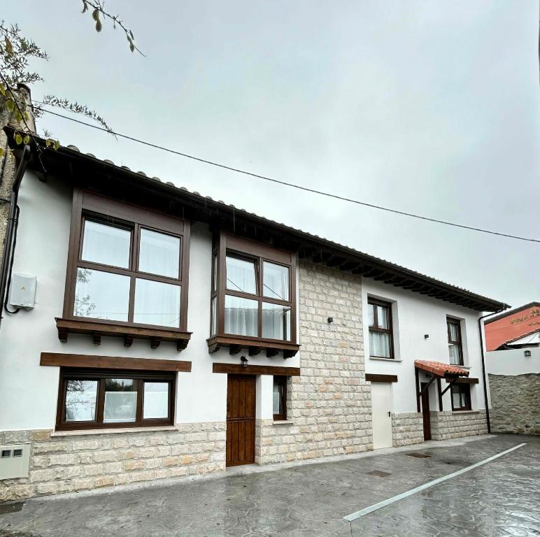 een wit bakstenen huis met bruine ramen bij Apartamentos El Calleral in Villahormes