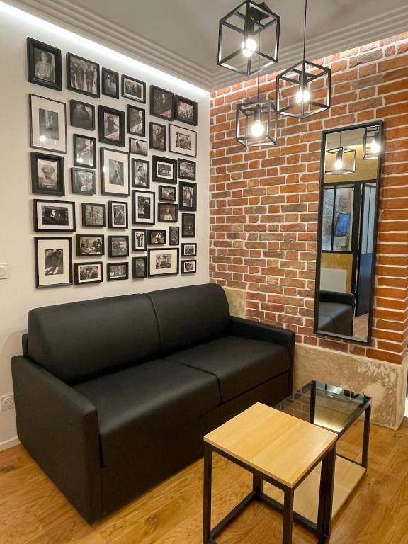 - un salon avec un canapé noir et un mur en briques dans l'établissement Cozy Loft Montmartre Place des Abbesses Sacré Cœur, à Paris