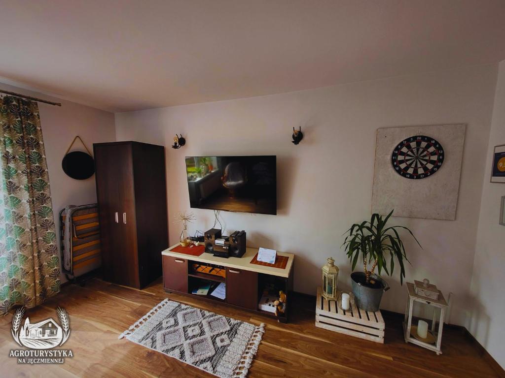 a living room with a table and a tv on the wall at Agroturystyka na Jęczmiennej - całe mieszkanie, 2 tarasy in Brodnica