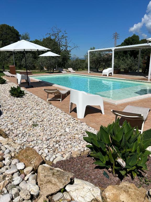 a swimming pool with chairs and an umbrella at Il Casaletto - Guest House in Terni