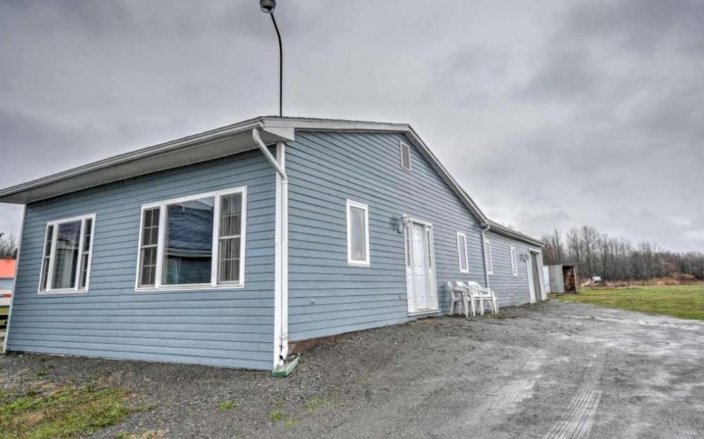 a small blue building with a lot of windows at Charming Four-Bedroom Cabin Rental near Long Lake in Aroostook County, Maine in Lavertue