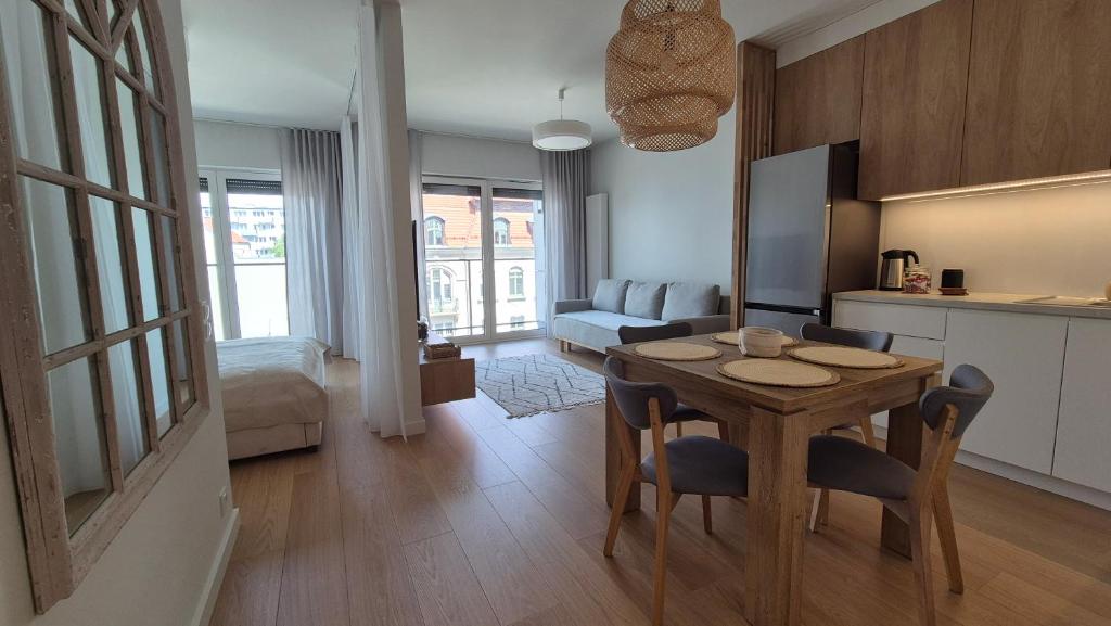 a kitchen and a living room with a table and chairs at Luxurious Cinnamon Apartment, self check-in 24h, free parking, air-conditioning in Poznań