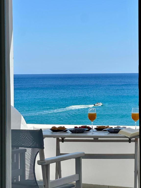 a table with two glasses of wine on the beach at Vista Del Mar Milos in Agia Kiriaki Beach