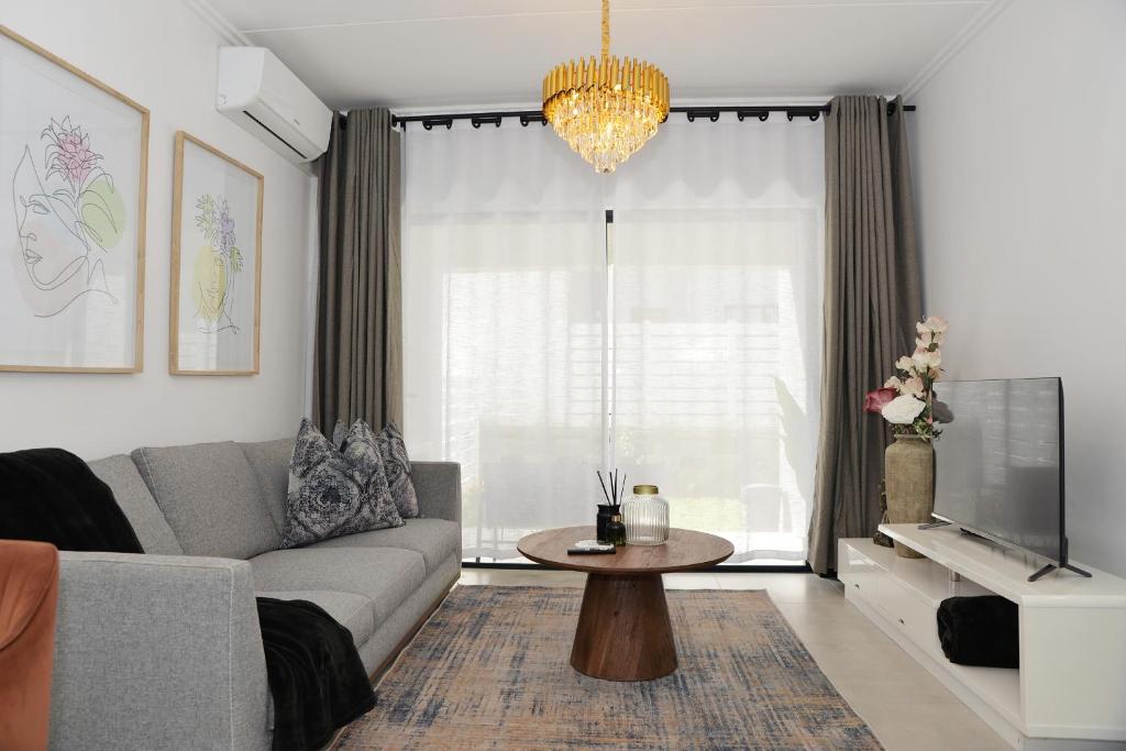 a living room with a couch and a tv and a table at Eirini Elegant Hestia Apartment in Sandton