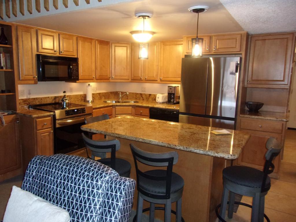 a kitchen with wooden cabinets and a island with bar stools at Crestwood 3305 Deluxe 1 Bedroom Plus Loft in Snowmass Village