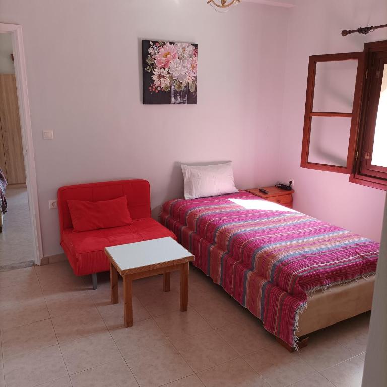a bedroom with a bed and a red chair at Pedi Breeze in Symi