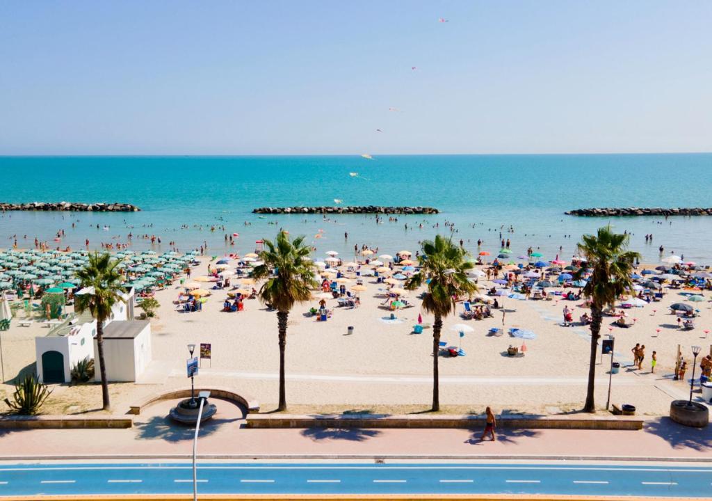 a beach with a crowd of people and the ocean at FAMILY KIDS VILLAGE Riva dei Pini in Lido di Fermo