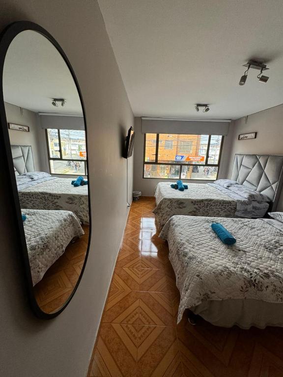 a room with four beds and a mirror at Gato Neon Hostel in Bogotá