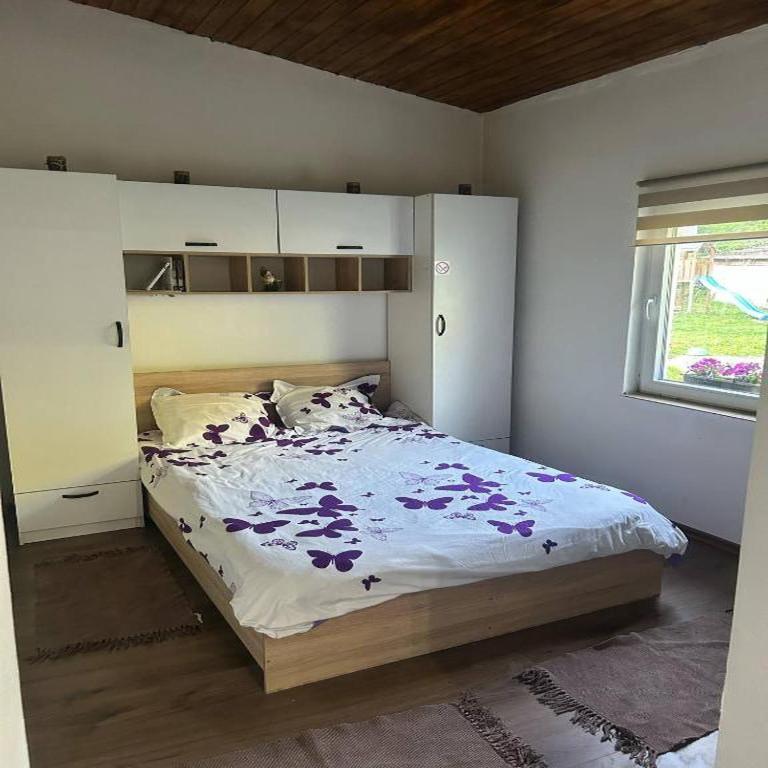 a bedroom with a bed with purple flowers on it at natoli in Căbeşti