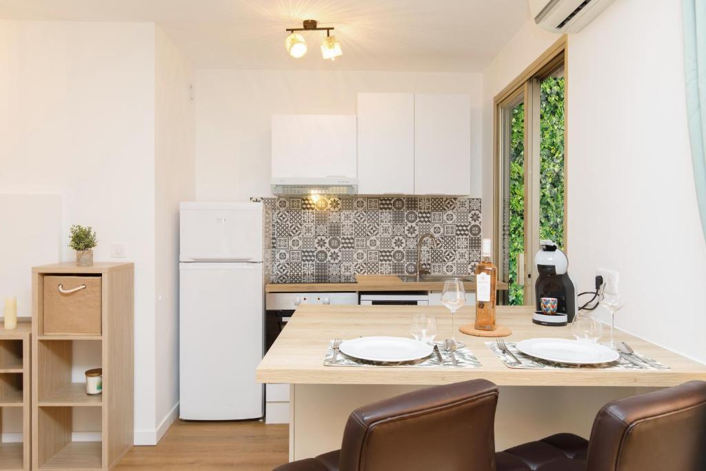 une cuisine avec une table avec des chaises et un réfrigérateur dans l'établissement Plein centre, calme et lumineux, à Mandelieu-la-Napoule