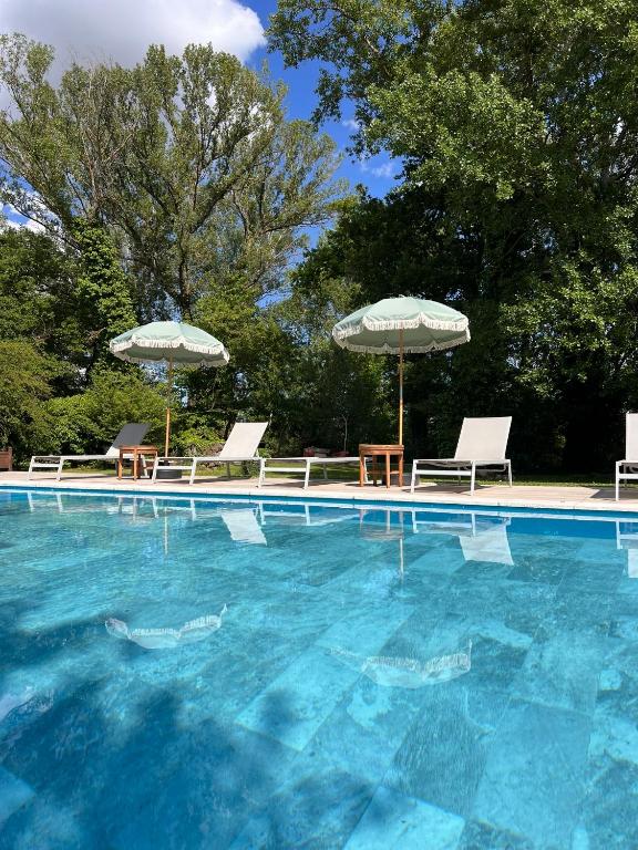 une piscine avec chaises et parasols dans l'établissement Le Moulin de Montségur, à Montségur-sur-Lauzon