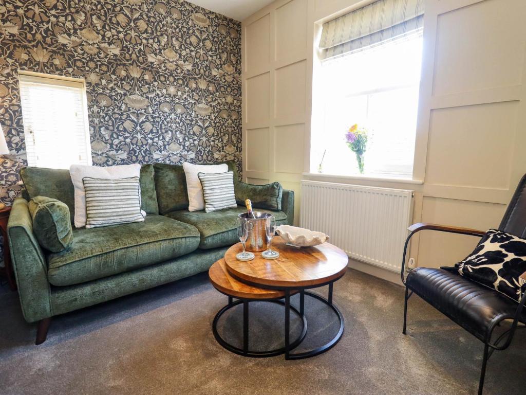 a living room with a green couch and a table at Gavel Cottage in Whitby