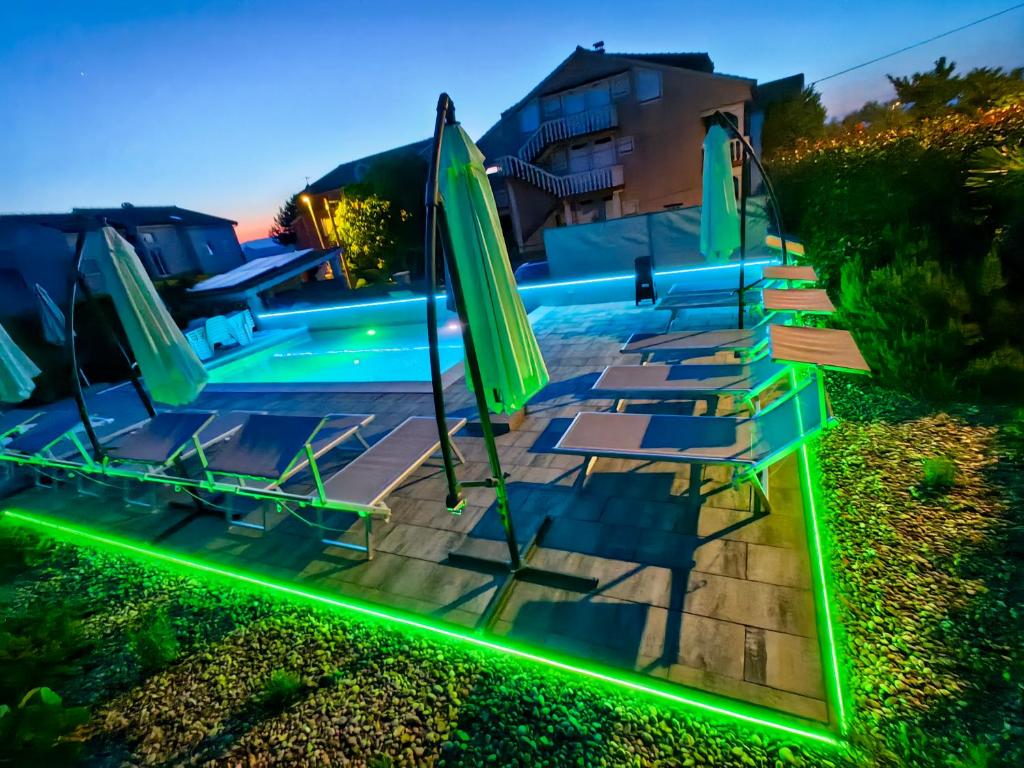 a group of chairs and umbrellas next to a pool at Apartments Lea with pool 2 in Malinska